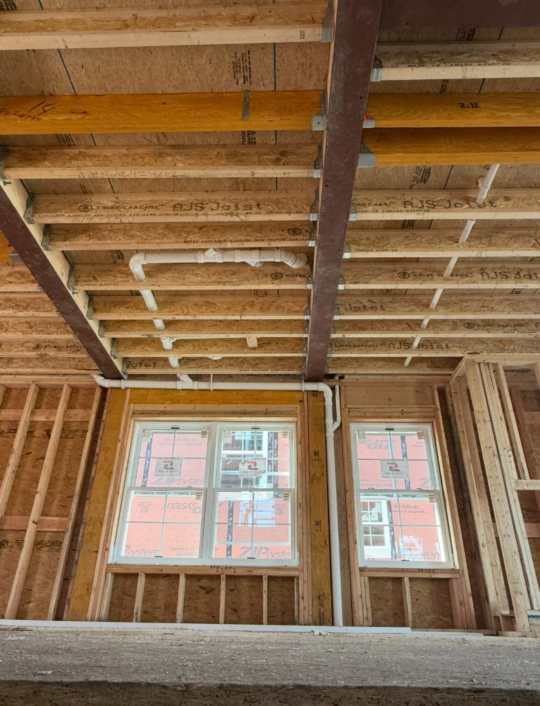 PVC drain and vent pipes rough-in through ceiling framing — Legacy Plumbing new construction