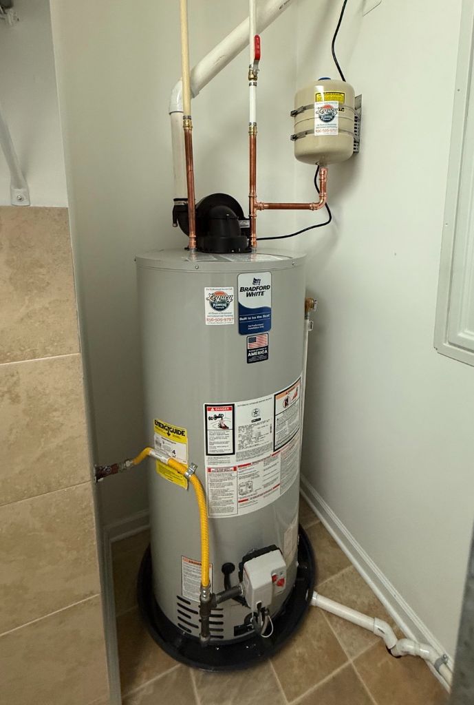 Bradford White tank water heater with expansion tank and yellow gas connector installed in a closet